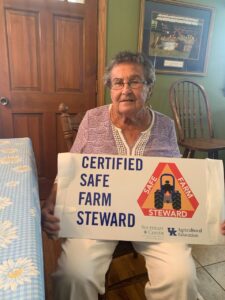 Woman holding a Certified Safe Farm Steward sign