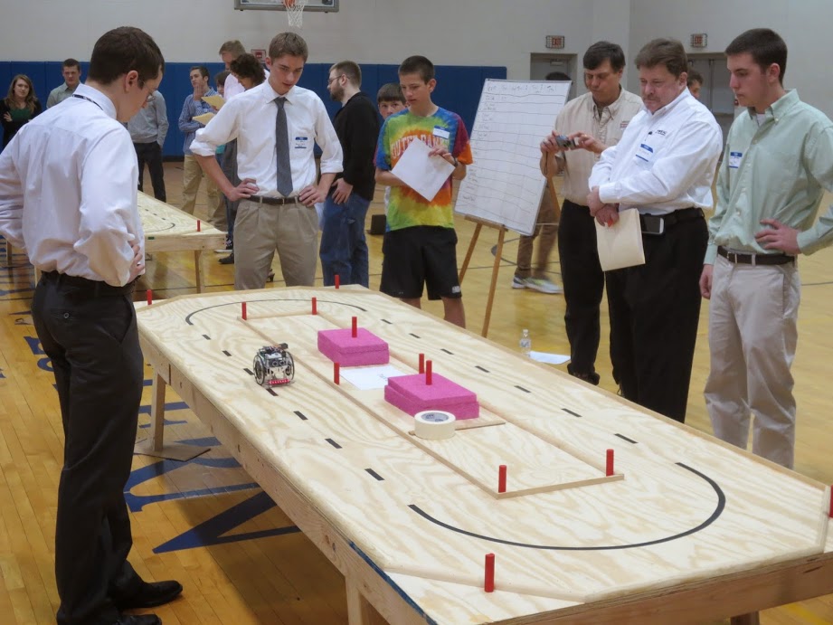 Students and judge viewing robotics track