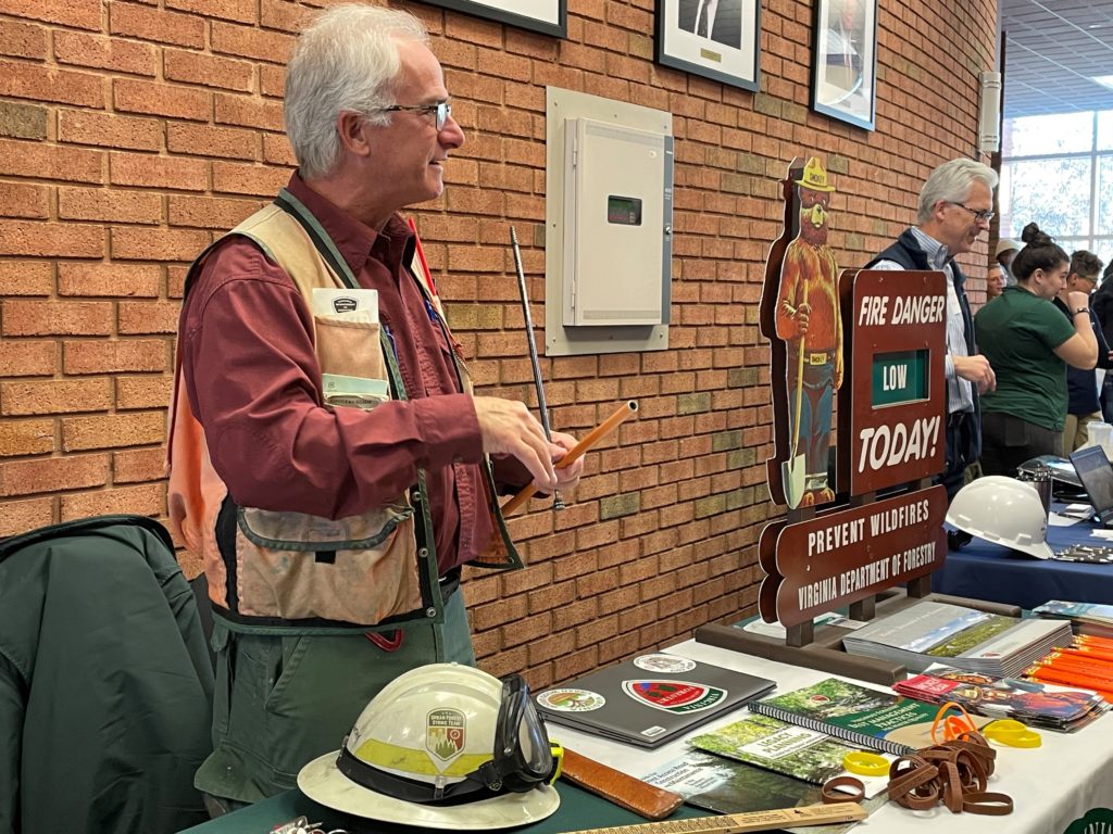Denny McCarthy (left) from the Virginia Department of Forestry helps students with the networking scavenger hunt at the start of the Earth Summit. Corporate Environmental Director Mark Aguilar of Titan America talks with summit attendees at the next table.