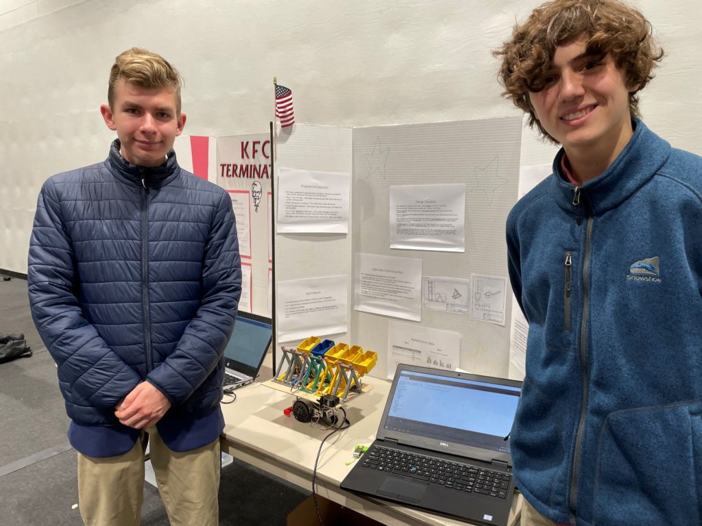 The team of Just Lucky, Regional Academy students Matthew Moshier (left) and Christian Harris, demonstrate their robot during the poster presentation section of the robotics competition. They later placed second among high school teams.