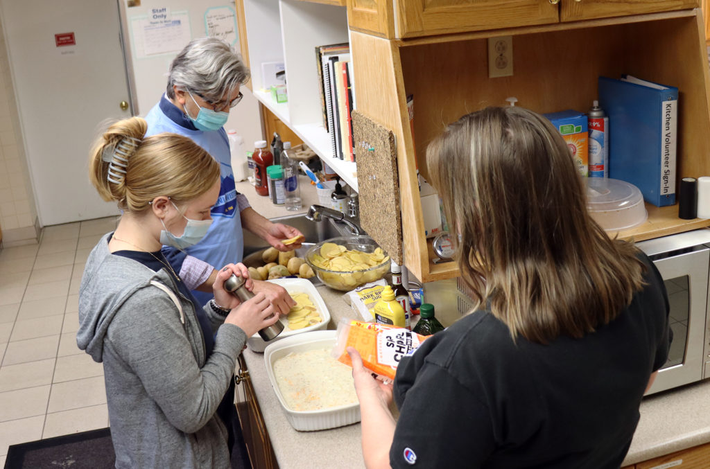 Andy Anguiano (from top), Christine Widener and Kitty Walls make scalloped potatoes for a side dish at the Ronald McDonald House. 