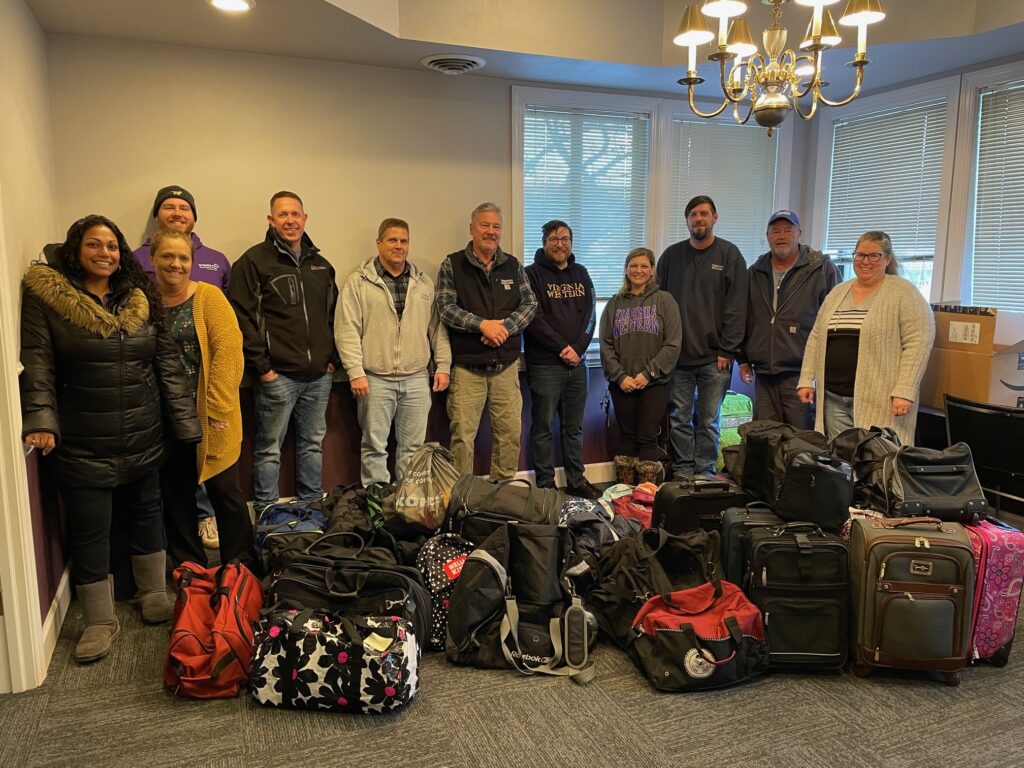 Embrace Treatment Foster Care staff members receive suitcase donations from Virginia Western Facilities Management Services staff and Day of Service volunteers at Embrace Treatment Foster Care's office in Roanoke County on Jan. 19.