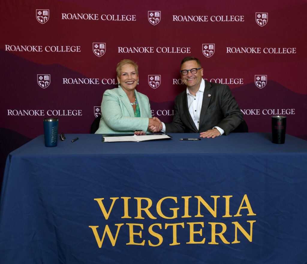 Virginia Western Community College President Laura Treanor and Roanoke College President Frank Shushok Jr. shake hands over a new biotechnology agreement between the two schools.