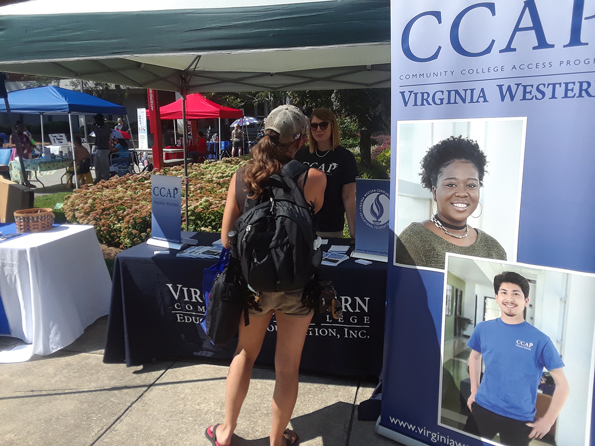 A student is obtaining information at the Community College Access Program (CCAP) table.