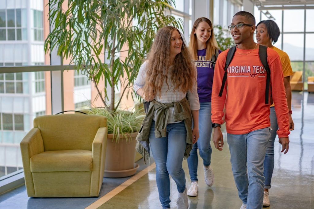 Students walking in Student Life Center, one with a Virginia Tech shirt and one with a James Madison University shirt