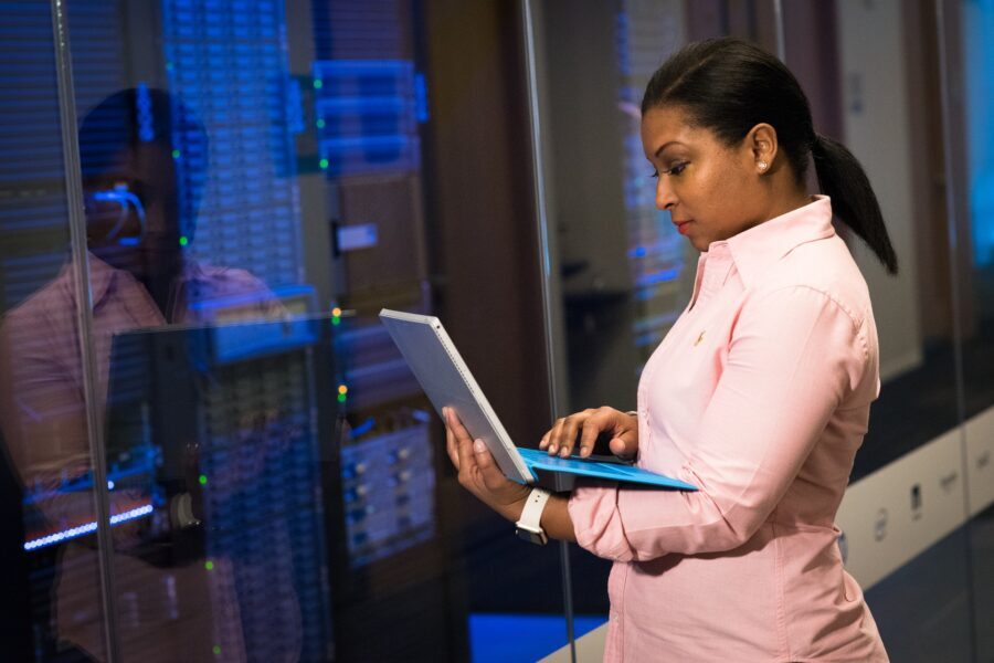 lady with laptop standing next to server bank